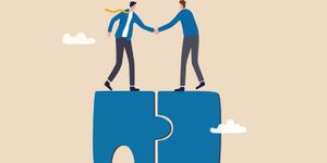 businessmen shhaking hands on jigsaw puzzle.