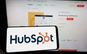 person holding mobile phone with hubspot logo on screen in front of web page.